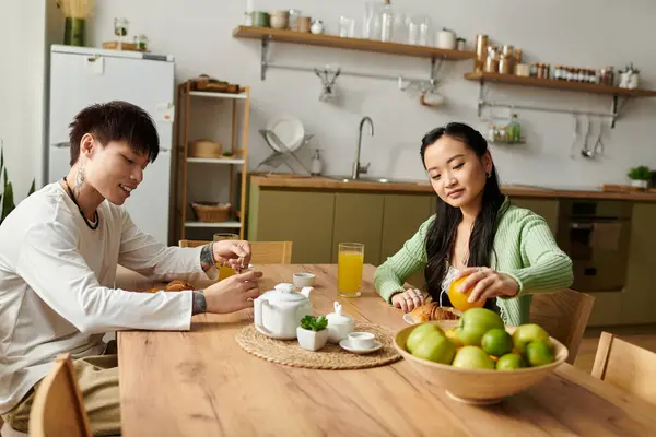A young Asian couple shares a delightful breakfast ritual, savoring food and drinks. — Stock Photo