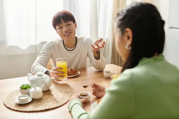 A young couple enjoys breakfast together, sharing laughter and a meal in their cozy kitchen. — Stock Photo