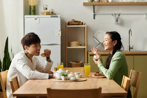 A young couple smiles and shares breakfast together in their cozy home kitchen. — Stock Photo