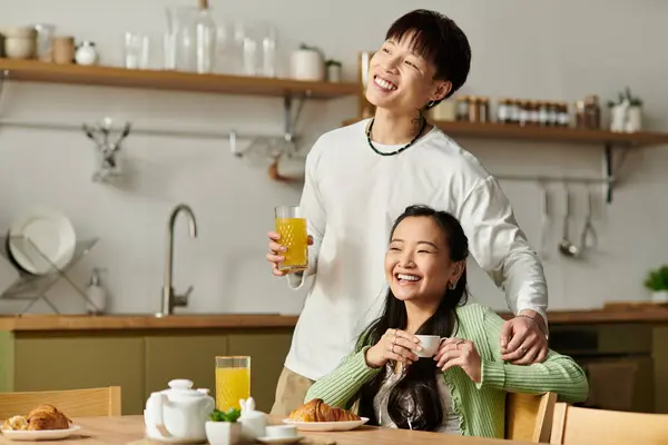 A young Asian couple enjoys a delightful breakfast together, laughing and sharing drinks. — Stock Photo