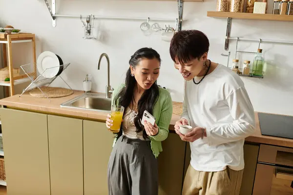 A young Asian couple shares laughter and breakfast at their cozy home, capturing a joyful moment. — Stock Photo