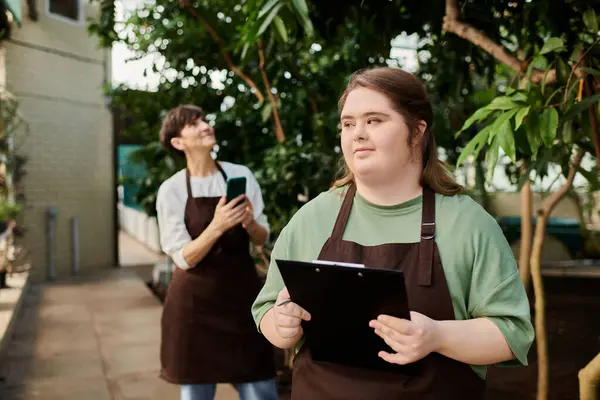 In a vibrant greenhouse, a woman guides her colleague as they nurture plants together. — Stock Photo