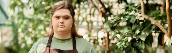 Confident young woman with Down syndrome works in greenhouse, nurturing plants and enjoying nature. — Stock Photo