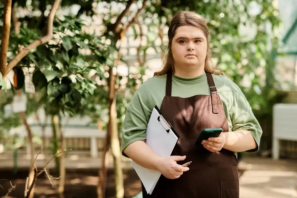 Young woman with Down syndrome confidently shines in a vibrant greenhouse. — Stock Photo