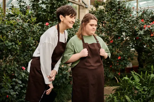 In a lively greenhouse, a mature woman shares insights with her young colleague with Down syndrome. — Stock Photo