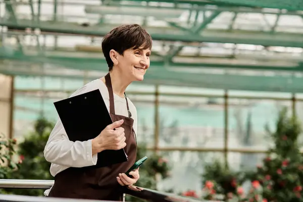 A confident woman thrives in a lush greenhouse, highlighting her dedication and beauty. — Stock Photo