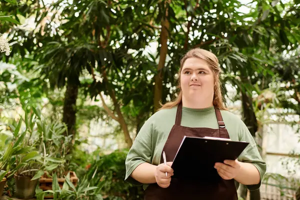 Young woman focuses on her tasks in a lush greenhouse, embodying confidence and determination. — Stock Photo