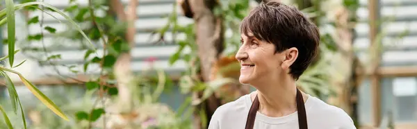 Confident woman nurtures plants in a lush greenhouse full of greenery. — Stock Photo