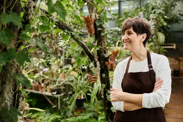 Confident woman interacts with flourishing plants while working diligently in the greenhouse. — Stock Photo
