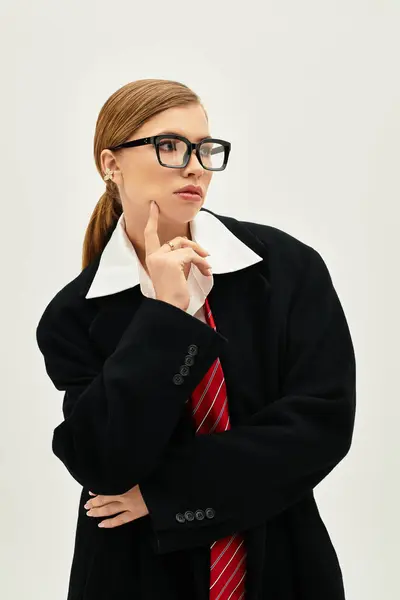 A young woman in trendy attire stands in a modern studio, lost in thought. — Stock Photo