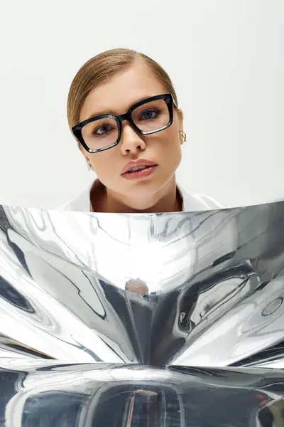 A young, beautiful woman confidently shows off her stylish glasses in the studio. — Stock Photo