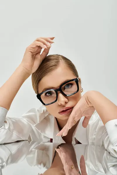 A stylish young woman displays poise while resting her hand on a reflective surface. — Stock Photo