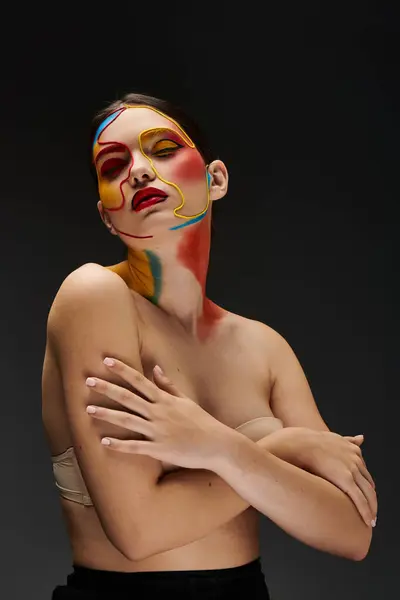 A young woman displays vibrant, artistic face makeup with bold colors and designs. — Stock Photo