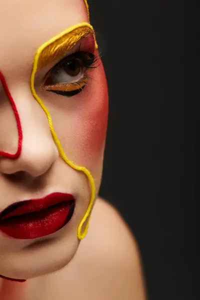 A vibrant young woman showcases bold face art and stylish makeup in bright colors. — Stock Photo