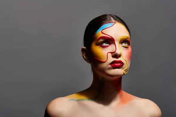 Une jeune femme affiche un visage art vibrant et un maquillage élégant dans un cadre créatif. — Photo de stock