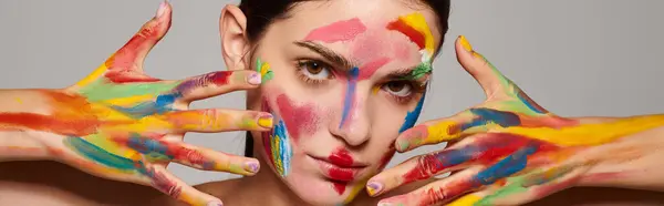 A young woman showcases vibrant face art, enhancing her beauty and artistic expression. — Stock Photo