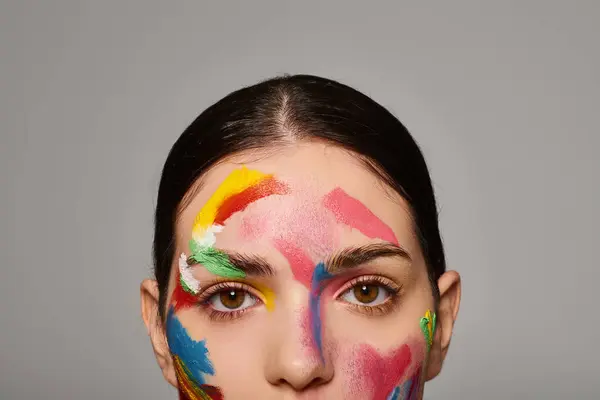 A beautiful young woman displays colorful face art, expressing creativity and style vividly. — Stock Photo