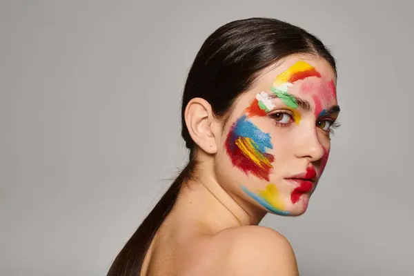 A young beautiful woman showcases vibrant face art with colorful patterns painted on her skin. — Stock Photo