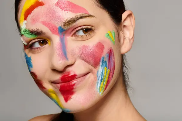 Une jeune femme affiche son art du visage coloré, rayonnant de créativité et de style. — Photo de stock