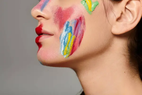 A stunning young woman flaunts vibrant face paint, radiating confidence and style. — Stock Photo