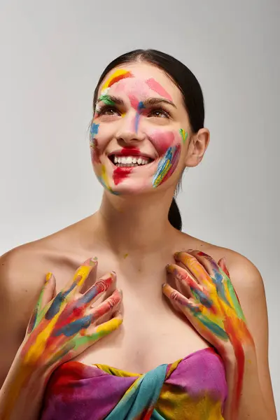 A young woman displays vibrant face art with colorful paint on her expressive features. — Stock Photo