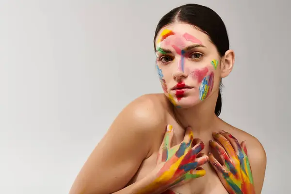 Bright colors adorn the face and hands of a young woman showcasing her unique artistic style. — Stock Photo