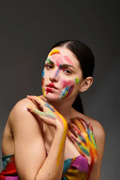 A young woman displays vibrant face art, showcasing her creativity with colorful paint. — Stock Photo