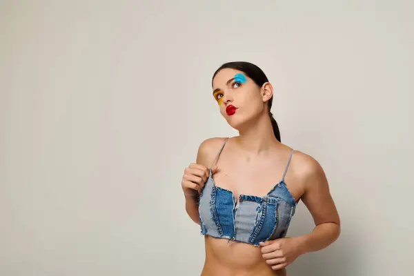 A young woman showcases artistic face paint and a trendy outfit, exuding confidence and charm. — Stock Photo