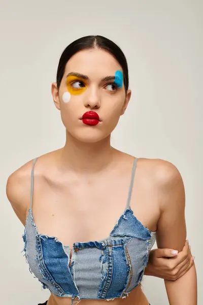 A young woman poses with artistic face paint in a vibrant, modern setting, capturing attention. — Stock Photo