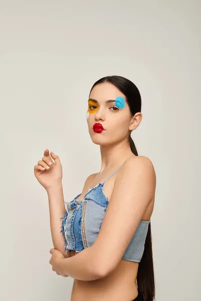 A young woman showcases her unique face art in vibrant colors, exuding creativity and confidence. — Stock Photo