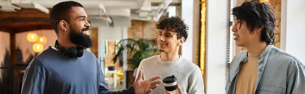 Three professionals share ideas and laughter while enjoying coffee in a vibrant workspace. — Stock Photo