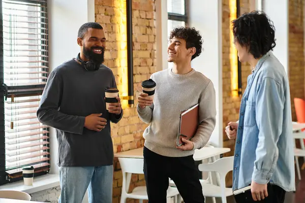 Three coworkers share ideas and coffee in a bright, relaxed office. — Stock Photo