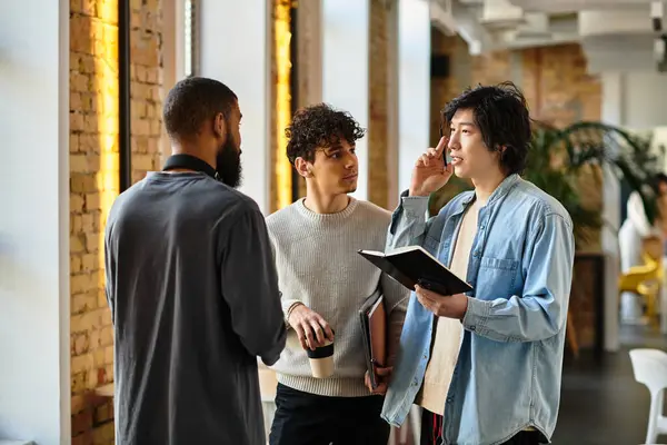 Three colleagues discuss and explore ideas in a bright, vibrant workspace. — Stock Photo