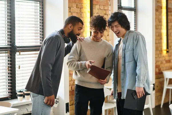 Three colleagues engage in cheerful discussion while reviewing a digital presentation together — Stock Photo