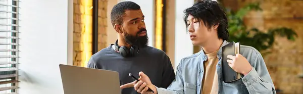Two professionals converse lively while working on a laptop in a chic office. — Stock Photo