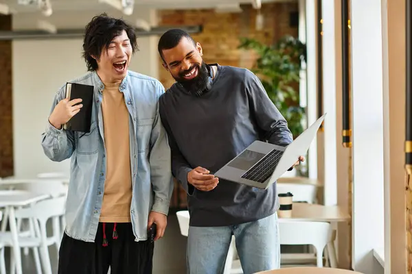 Two coworkers chat lively while reviewing documents and a laptop in a modern setting. — Stock Photo