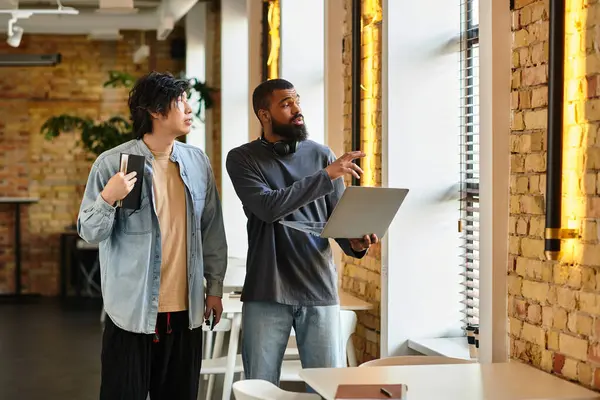 Two professionals discuss ideas while standing near large windows in a stylish office. — Stock Photo