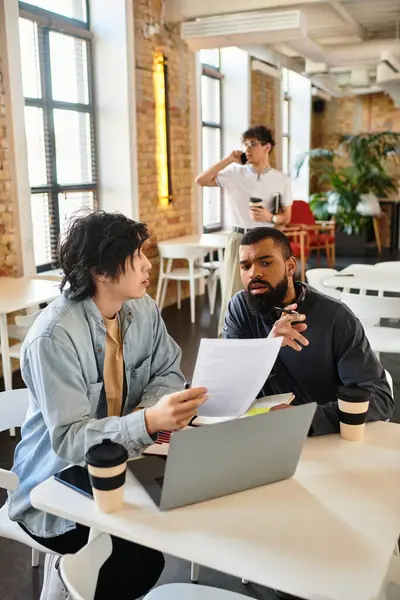 Zwei Kollegen diskutieren dynamisch, während sie Dokumente an einem gemeinschaftlichen Arbeitsplatz sichten. — Stockfoto