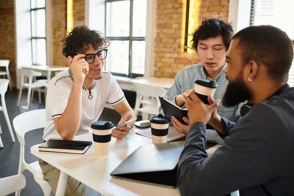 Três profissionais colaboram em um espaço de trabalho moderno, compartilhando ideias e desfrutando de café. — Fotografia de Stock