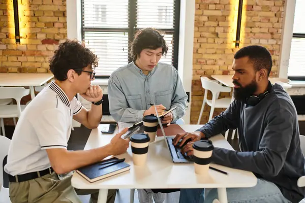 Tre individui si impegnano in una discussione produttiva mentre lavorano sui loro computer portatili e notebook. — Foto stock