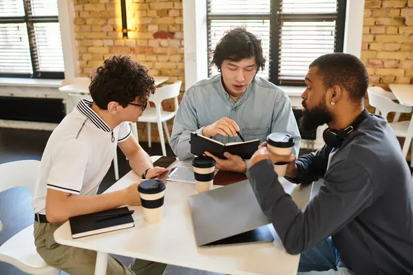 Three professionals collaborate at a bright office table, sharing notes and drinks. — Stock Photo
