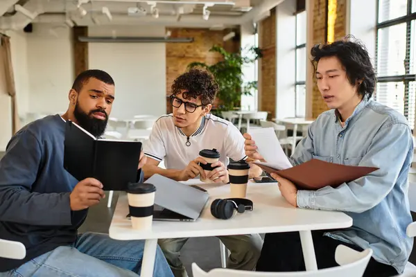Three colleagues engage in a focused discussion, analyzing documents and sharing ideas over coffee. — Stock Photo