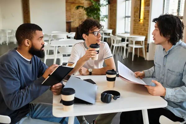 Three professionals chat animatedly over coffee while reviewing documents in a chic office. — Stock Photo