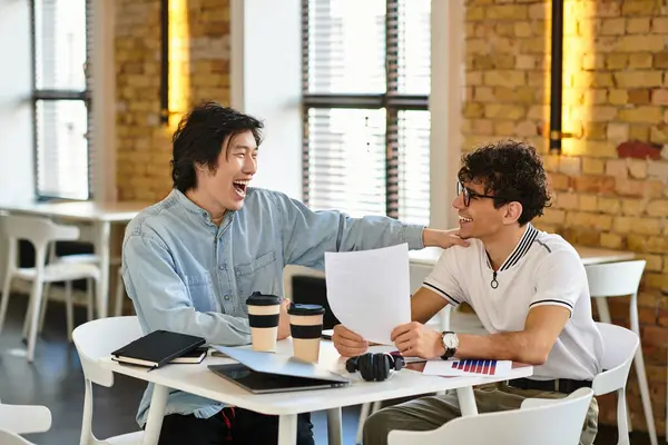Zwei Menschen teilen Lachen und Ideen an einem Tisch in lebendiger Atmosphäre. — Stockfoto