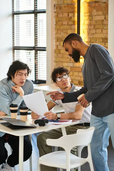 Três profissionais discutem e revisam documentos em uma mesa em um espaço de trabalho brilhante. — Fotografia de Stock