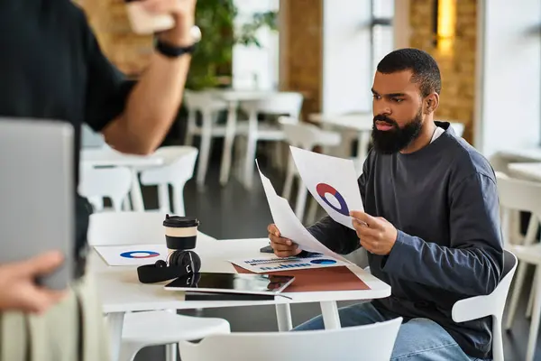 Two colleagues engage in a detailed conversation while reviewing reports and drinking coffee. — Stock Photo