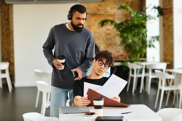 Zwei Personen diskutieren lebhaft, während sie Dokumente in einem trendigen Arbeitsbereich sichten. — Stockfoto