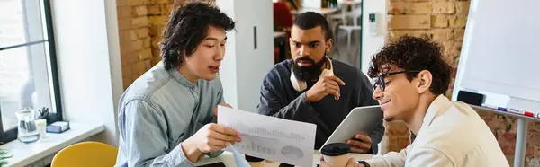 Three professionals discuss and review documents in an open office. — Stock Photo
