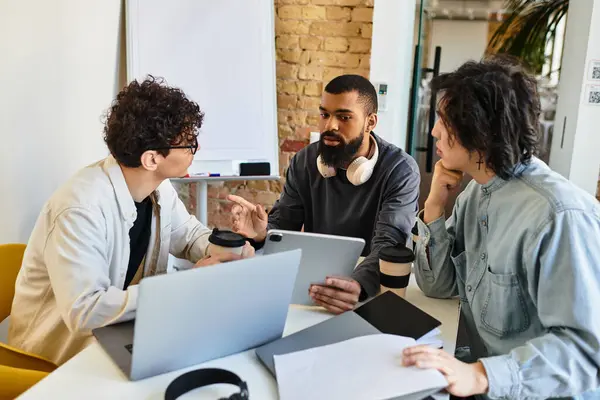 Three professionals discuss ideas in a collaborative workspace with tech tools. — Stock Photo