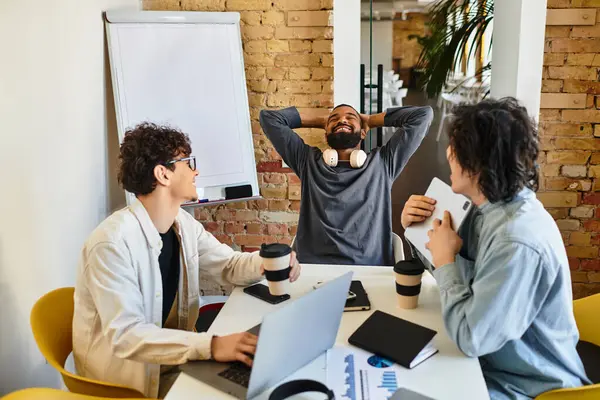Group of colleagues engaging in a lively discussion while enjoying coffee in a modern workspace. — Stock Photo